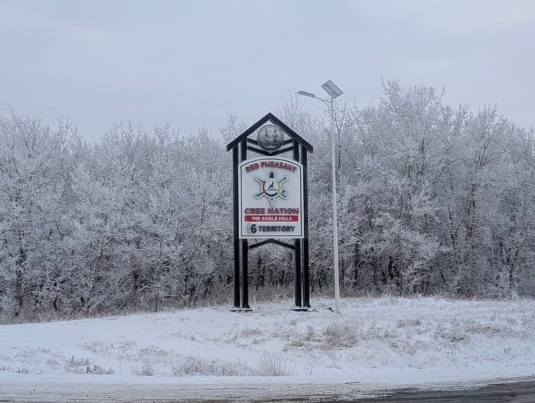 The Red Pheasant Cree Nation sign in winter, with frosted trees behind it