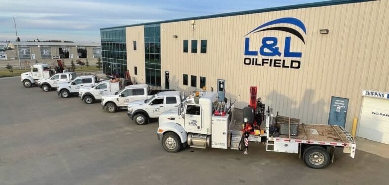 The L&L Oilfield shop with a row of white company trucks and a picker truck parked out front